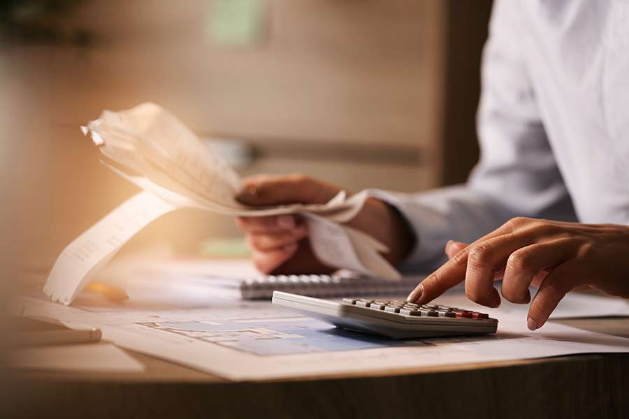 Person calculating expenses with a calculator while reviewing utility bills