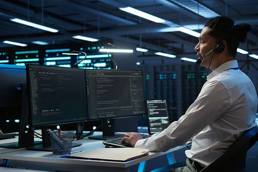 cybersecurity analyst monitoring network systems on a desktop in a high-security server room